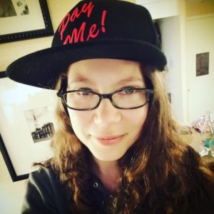 blogger Epiphora wearing a hat that says "Pay Me"