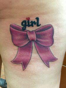 one of my thigh tattoos: a pink bow with the word "girl" above it