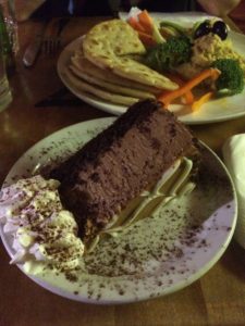 a slice of dulce de leche cheesecake and a plate of hummus and veggies